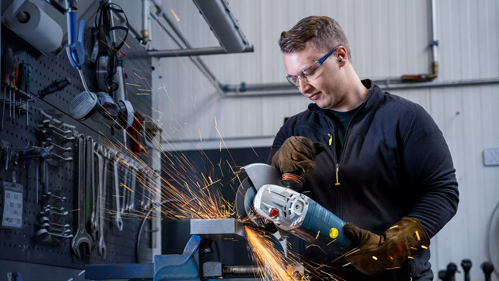 Mitarbeiter bearbeitet ein Metallwerkstück mit einem Winkelschleifer.