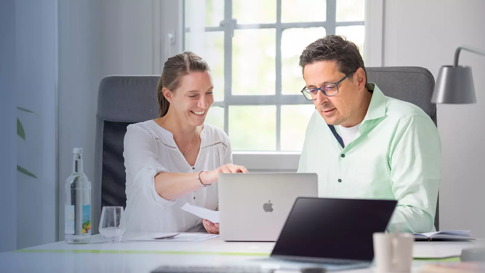 Zwei Personen besprechen gemeinsam Inhalte am Laptop im Büro.