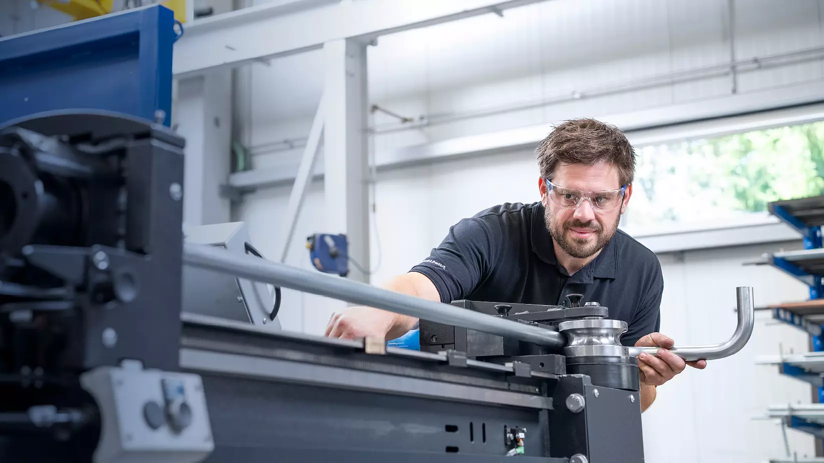 Mitarbeiter bei der Arbeit an einer Biegemaschine in einer Produktionshalle.