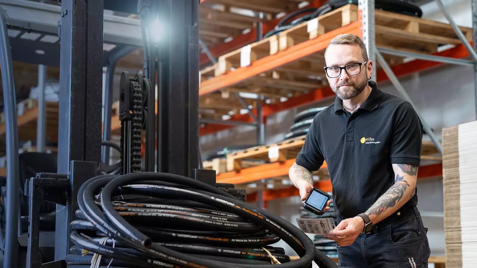 Mitarbeiter im Lager bei der digitalen Erfassung von Waren neben einem Gabelstapler.